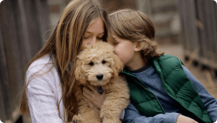 Two children kissing a puppy